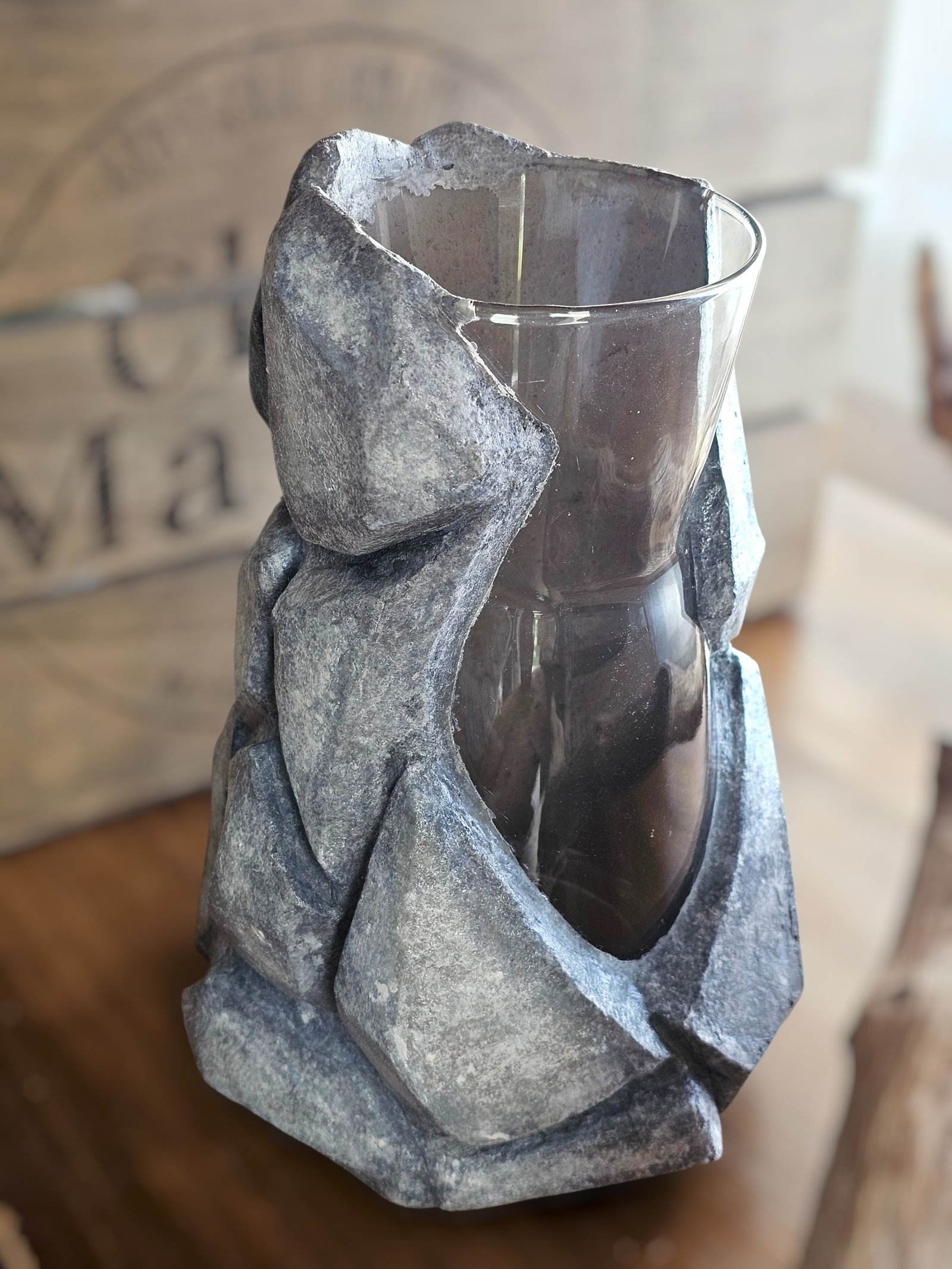 Sculptural Gravik vase — a glass vessel wrapped in a fractured grey concrete form